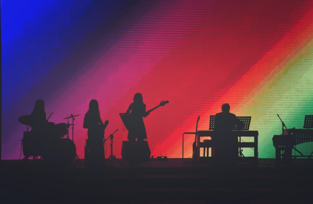 A band playing against a rainbow background image