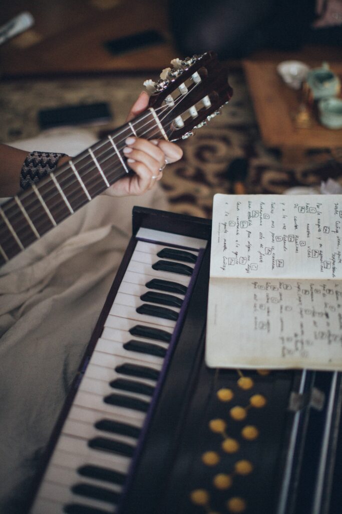 A person holding a guitar sitting in front of a guitar and a notebook image