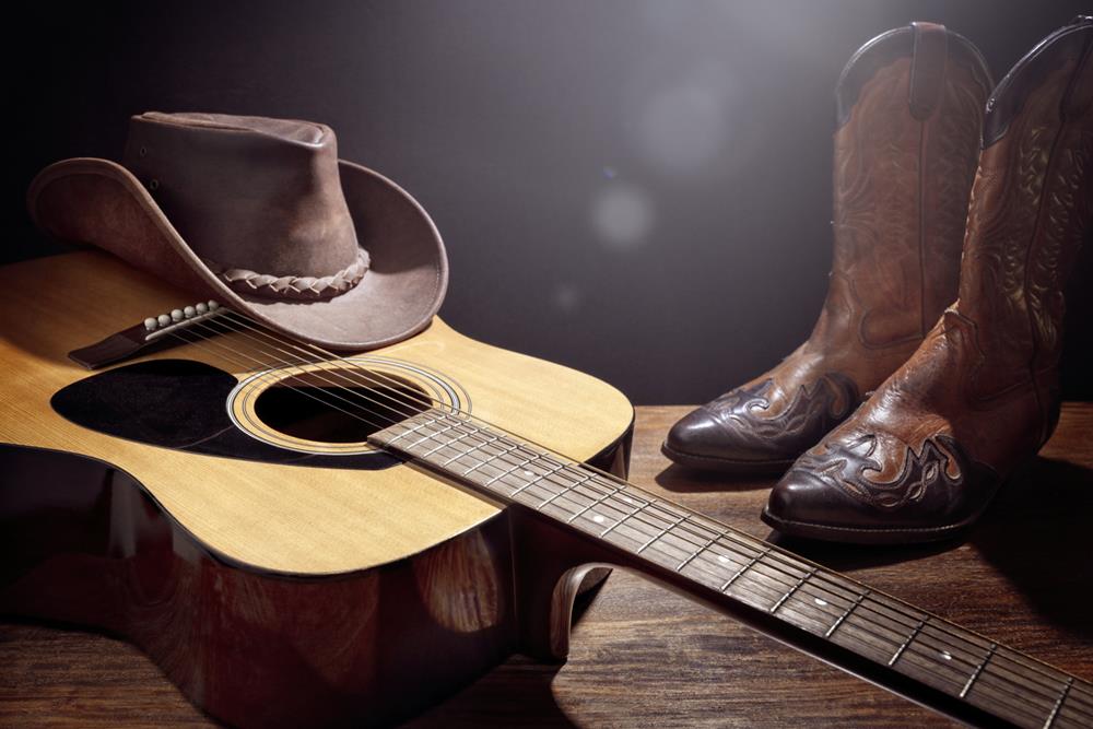 Acoustic guitar with cowboy hat and shoes showcasing country music