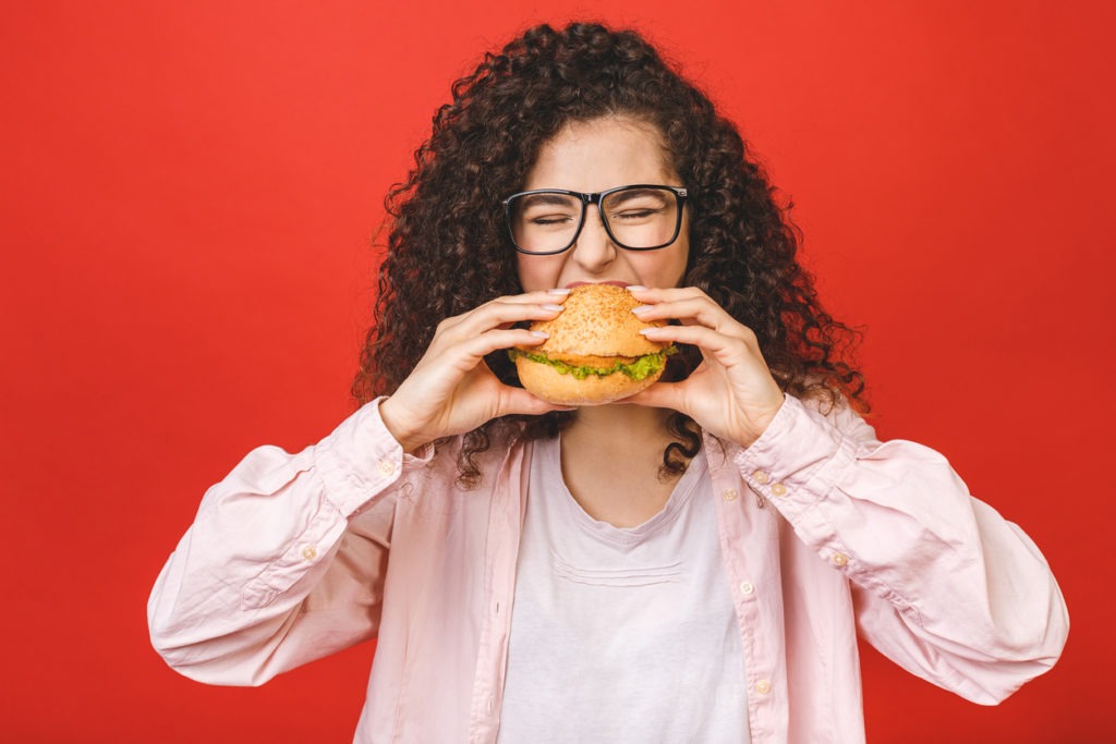 Woman eating a burger she bought from a fast food