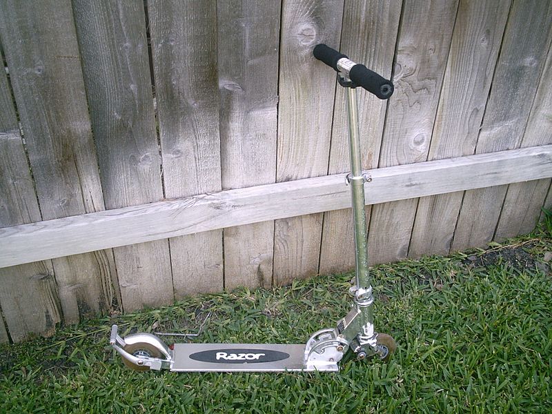 A Razor Scooter by a fence
