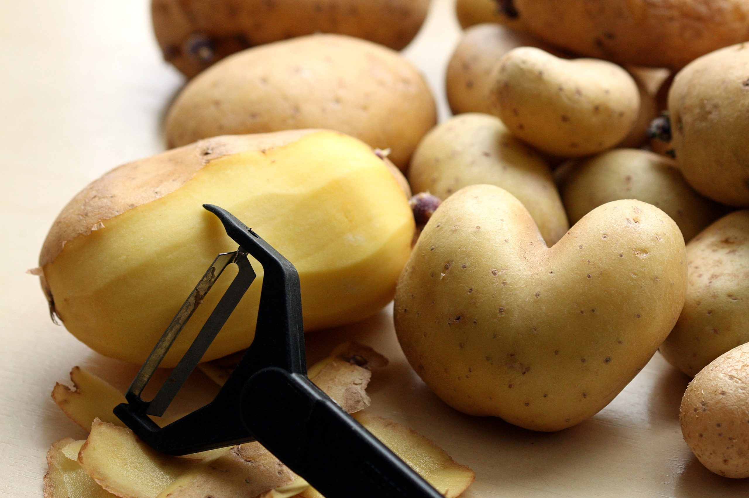 An Image of potatoes with a peeler