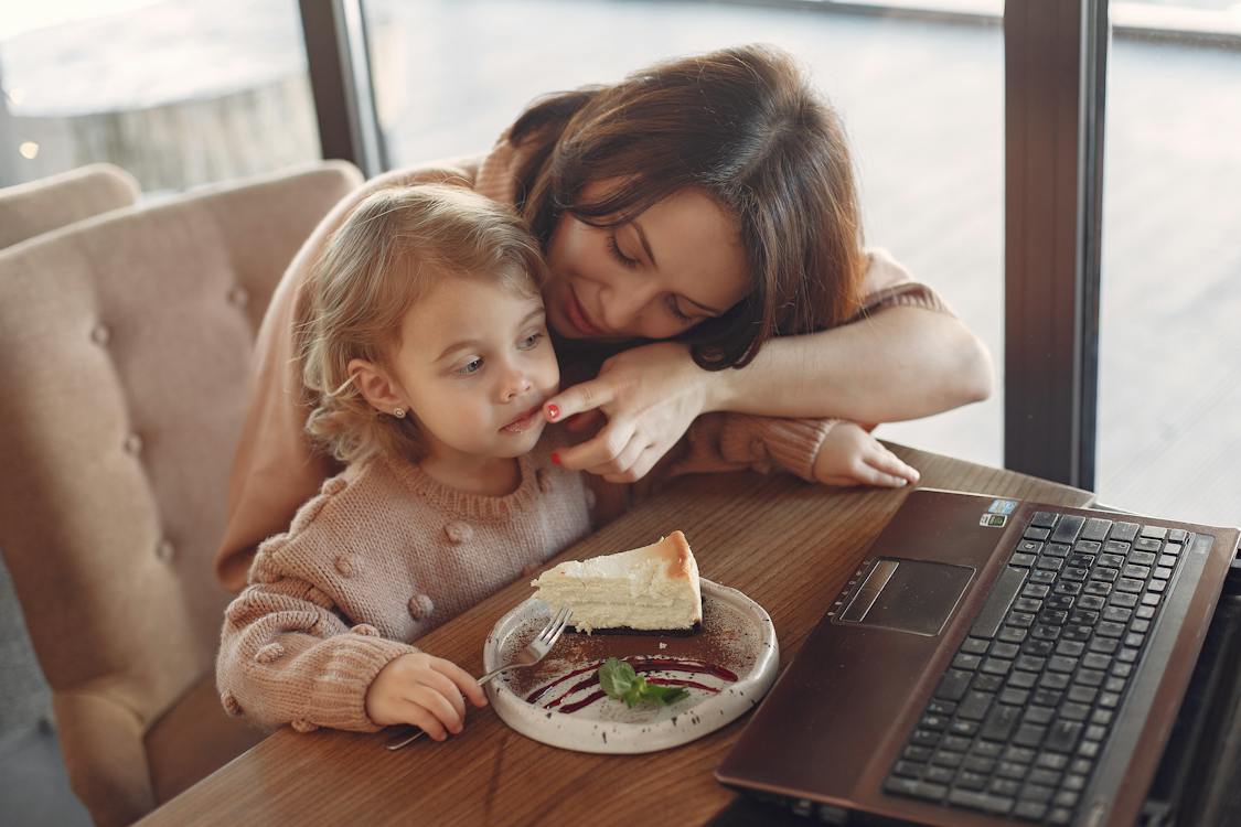 Mother and daughter with laptop in cafe