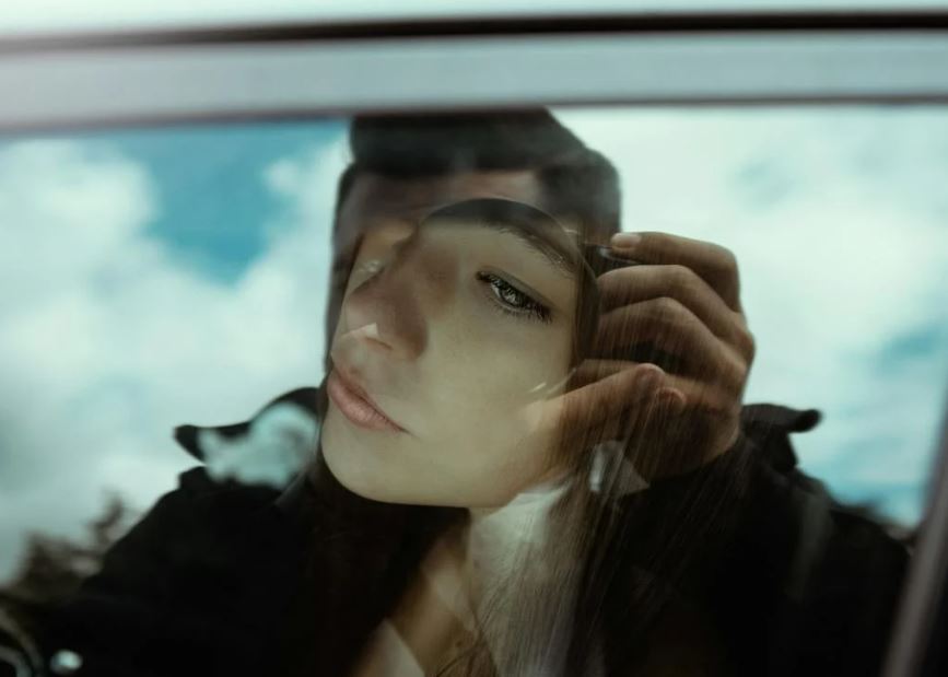 Thoughtful woman looking through car windowThoughtful woman looking through car window