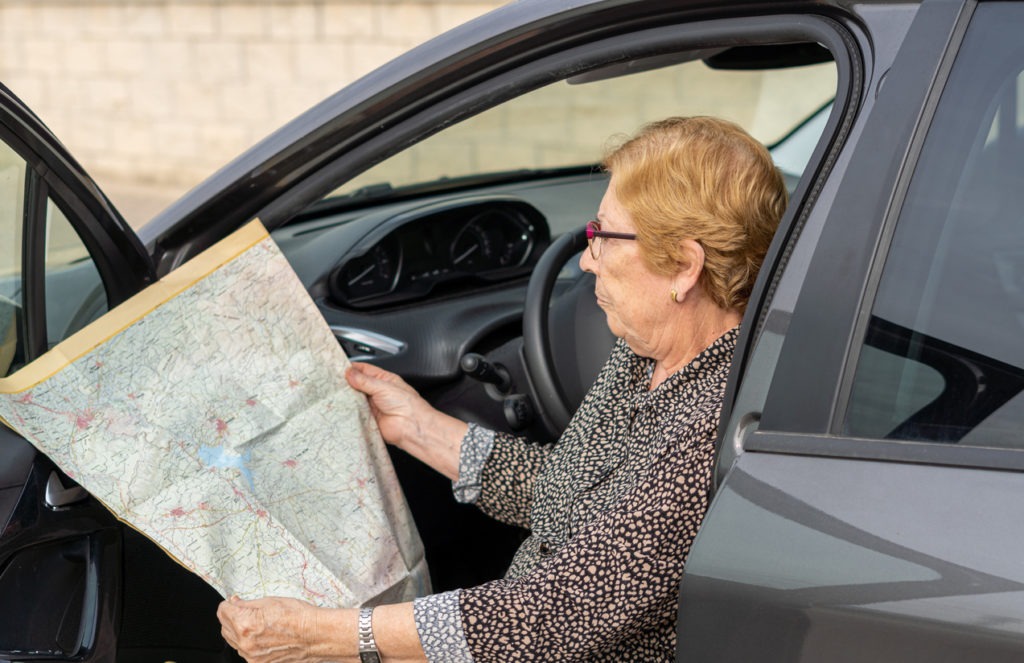 Senior woman looking at a paper map sitting in a car