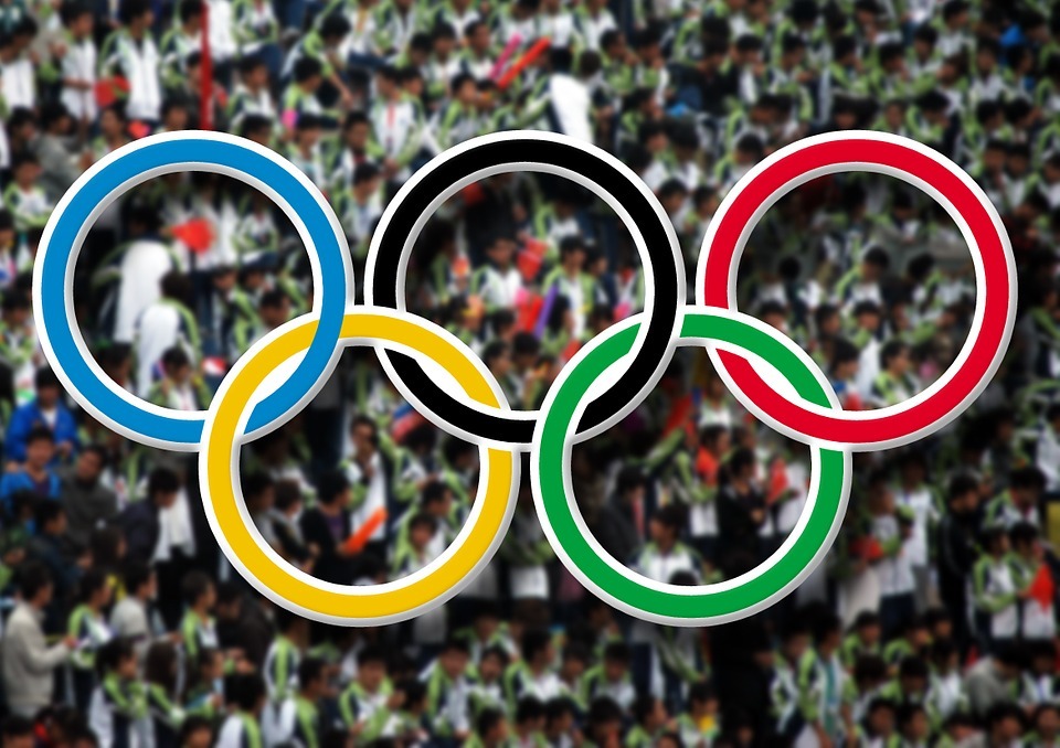 A photo of the Olympics logo with the competitors on the background