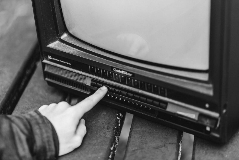 person pressing a button on an old television