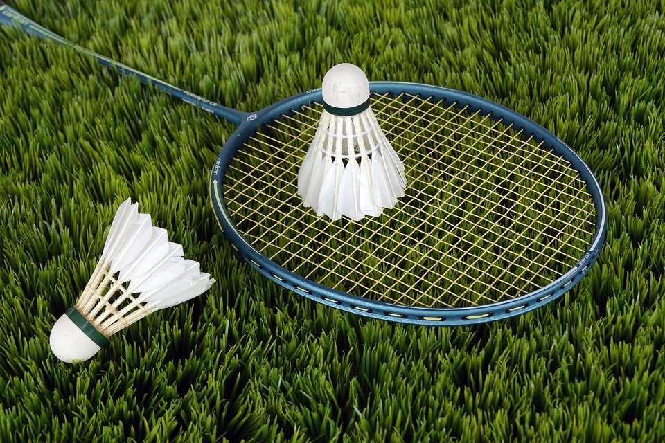 Two shuttlecocks with a badminton racket placed on the grass