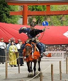 a Yabusame player on a horse while shooting at a target