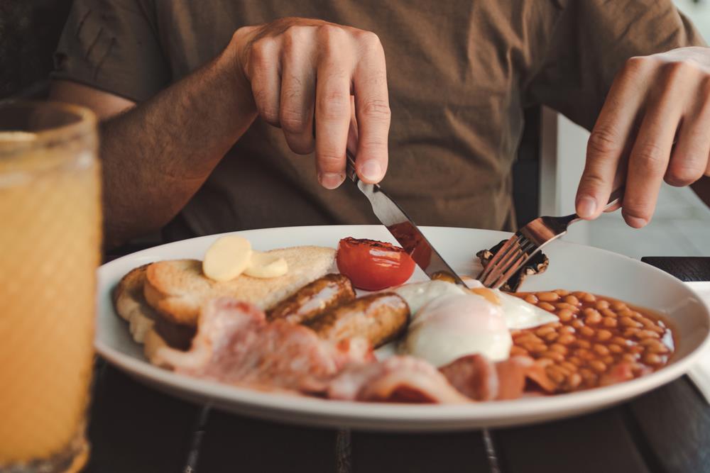 Person enjoying a plate of English breakfast