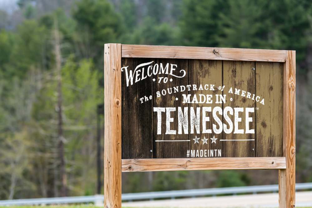 Welcome to Tennessee sign at border with wooden board and text for soundtrack of America and hashtag