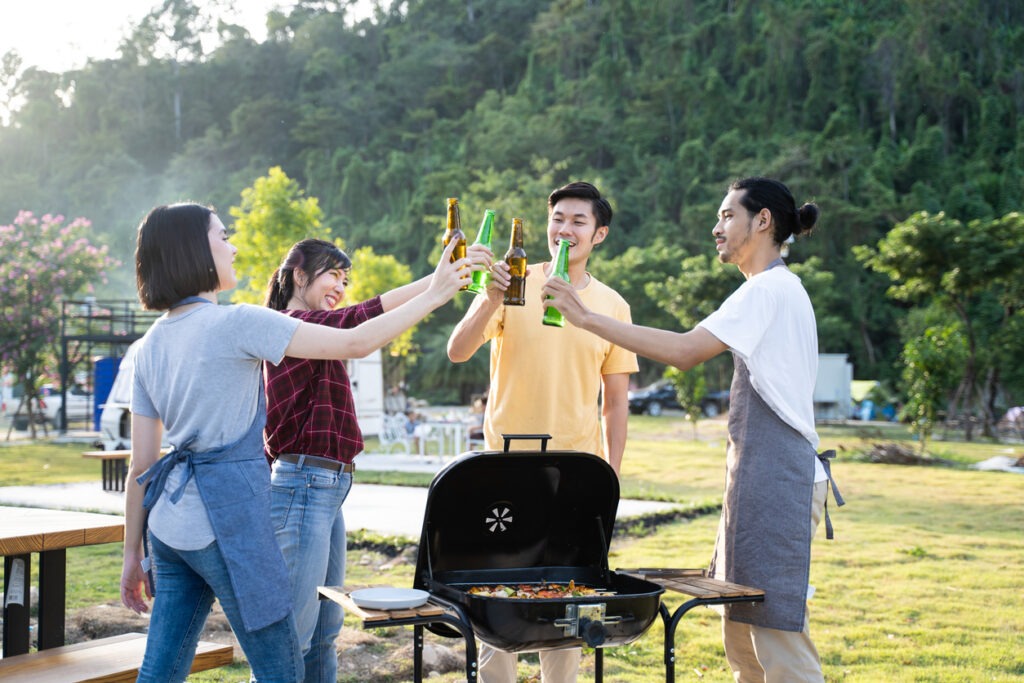 a group of Chinese friends having a simple gathering outdoors, grilling and drinking beer
