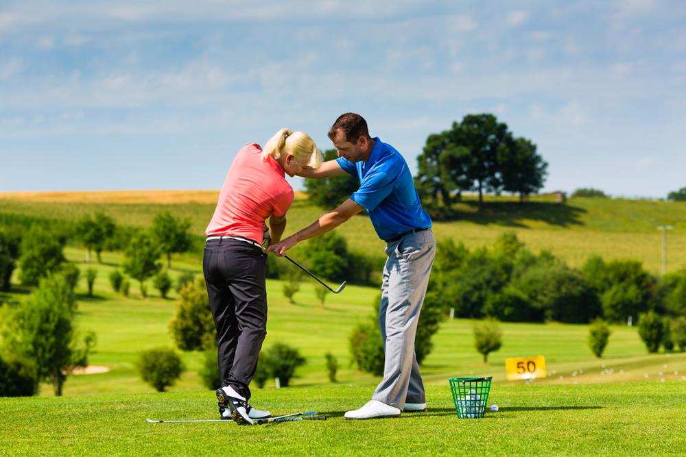 A golf instructor teaching a woman