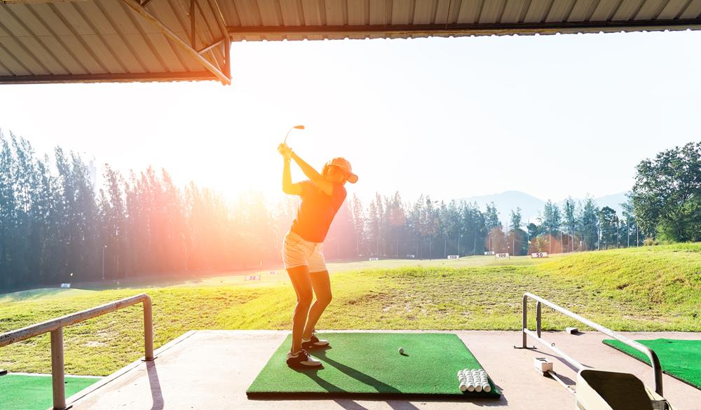 Woman practices her golf swing on driving range