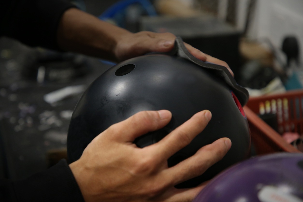 A pair of hands holding a bowling ball and polishing pad for the finishing touch.
