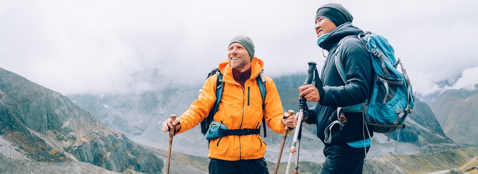 Caucasian and Sherpa men with backpacks with trekking poles together smiling enjoying Mera peak climbing acclimatization walk Makalu Barun Park route. Backpackers enjoying beautiful valley view