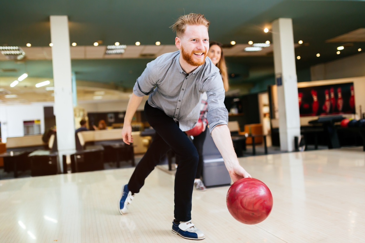 Handsome man bowling in the club and throwing the ball