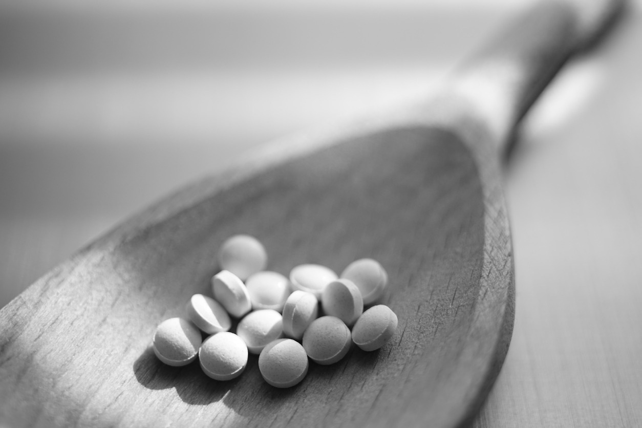Medical pills in a wooden spoon closeup. Black and white photo