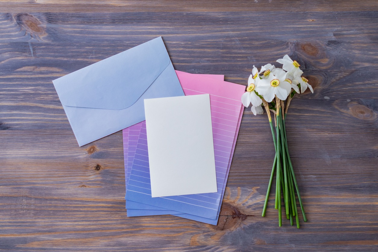 Mockup wedding invitation and envelope with white daffodils on a wooden table