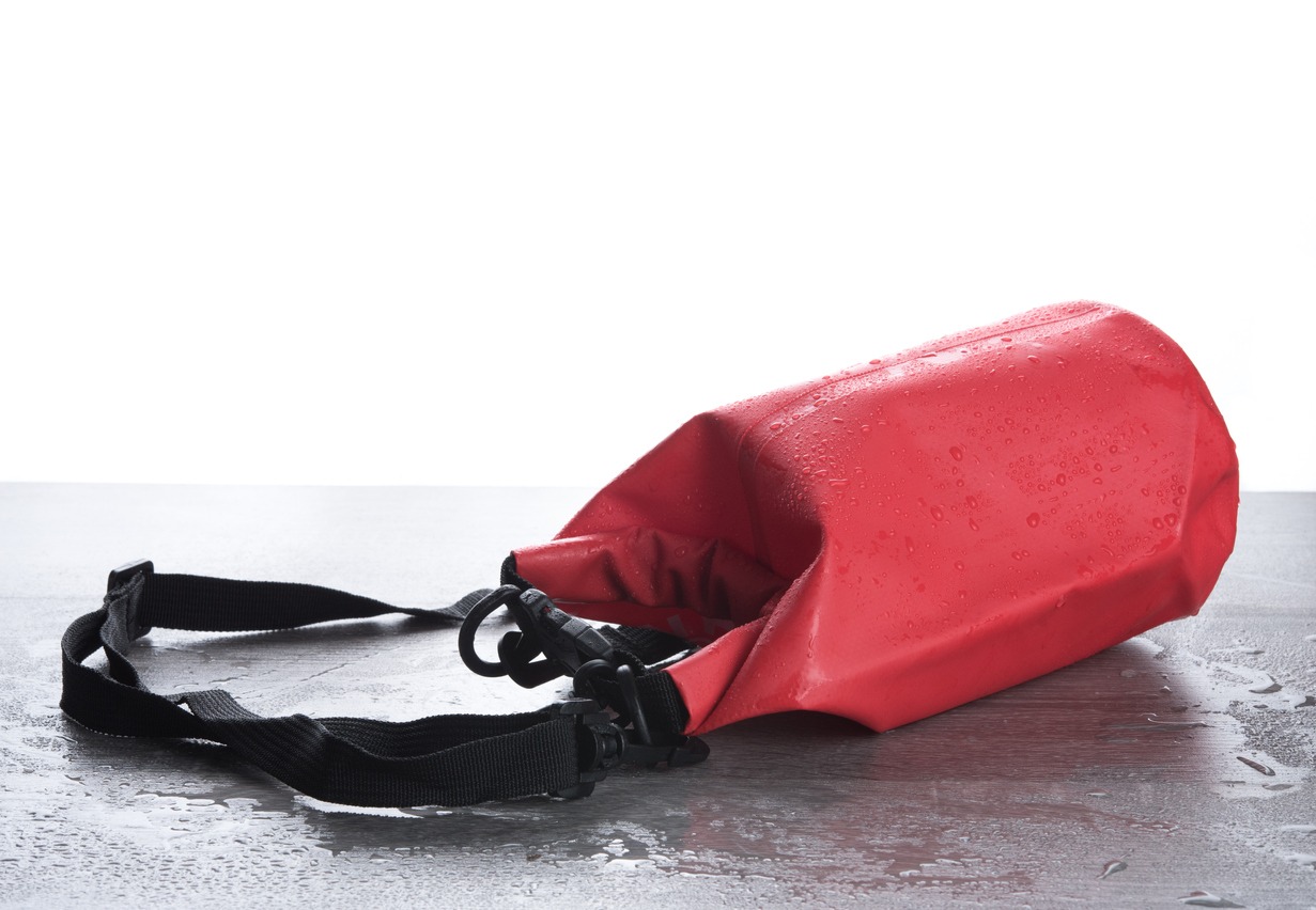Red waterproof bag to protect your belongings from water on a wooden table