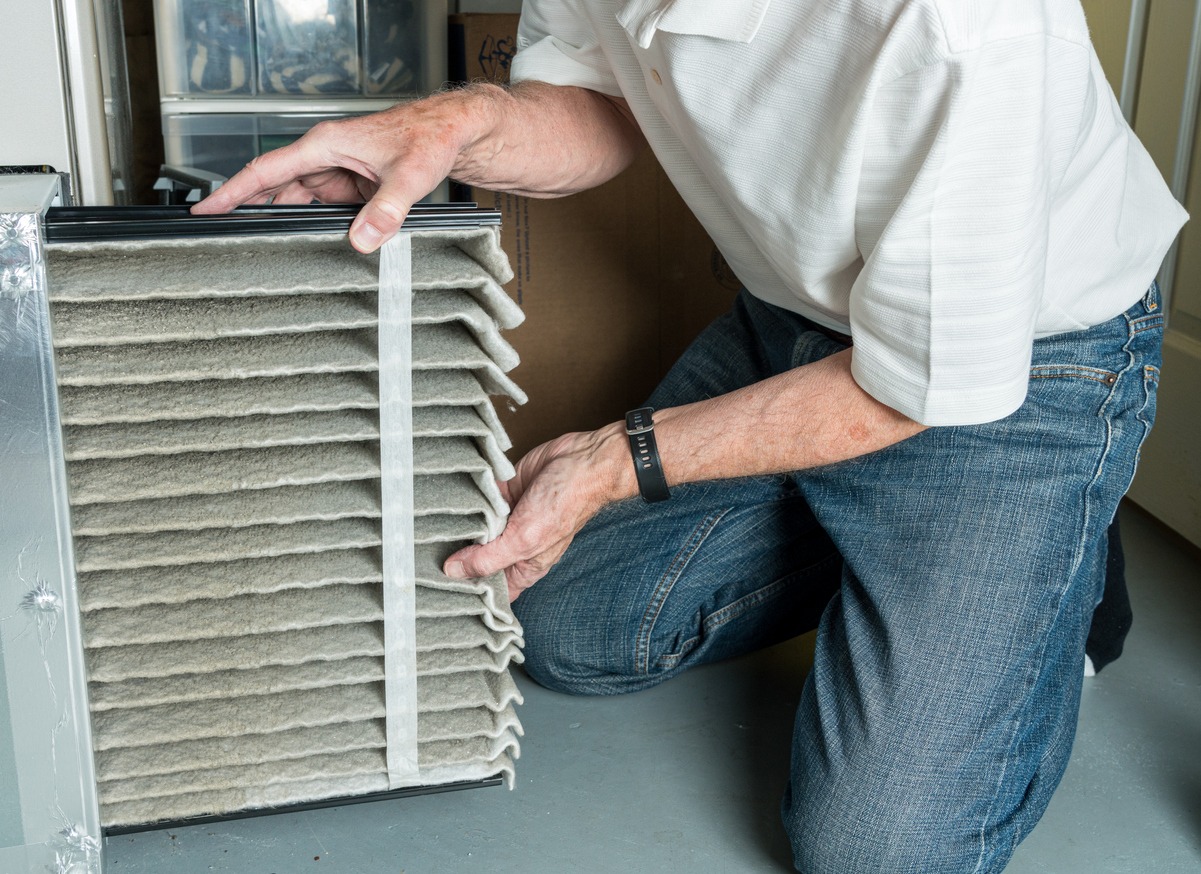 Replacing dirty furnace filter in the home by a man