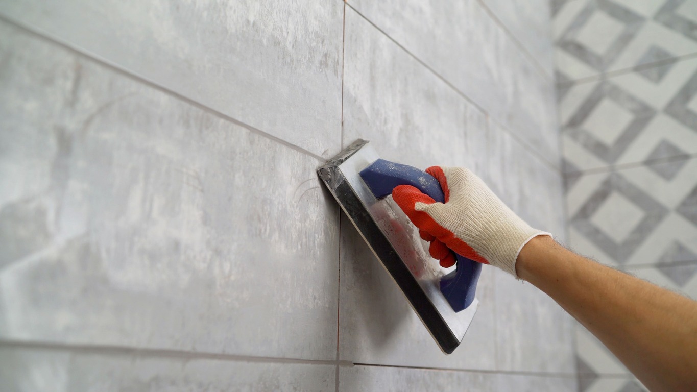 Seam grouting with black grout. Tile grout. Construction work with ceramic tiles. Grouting, and joining wall tiles. The builder processes the seams between ceramic tiles