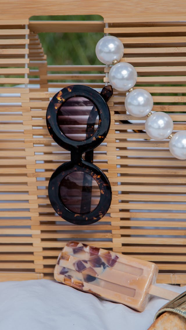 A Round Black Framed Sunglasses Hanging on a Bamboo Bag