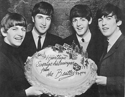 The Beatles holding a cake