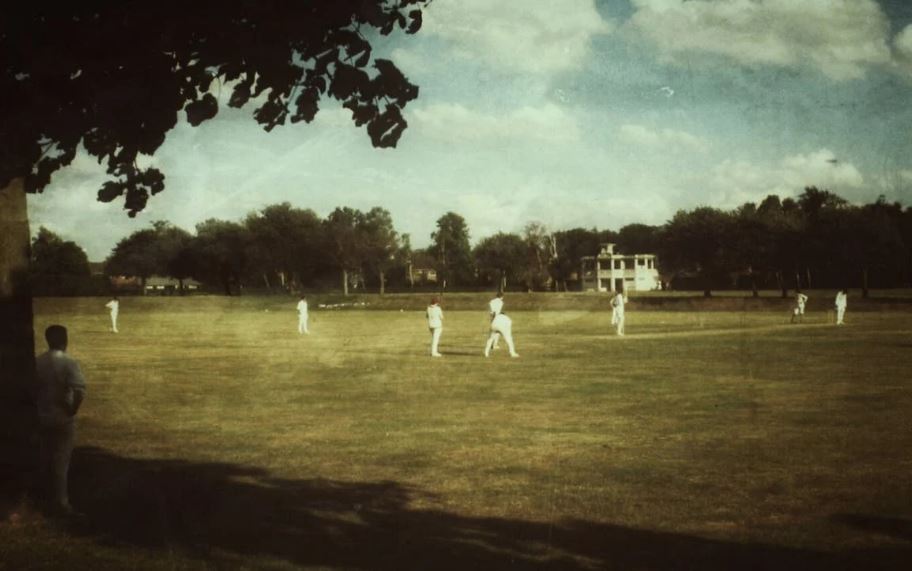 People in White Clothes Playing Cricket on the Field