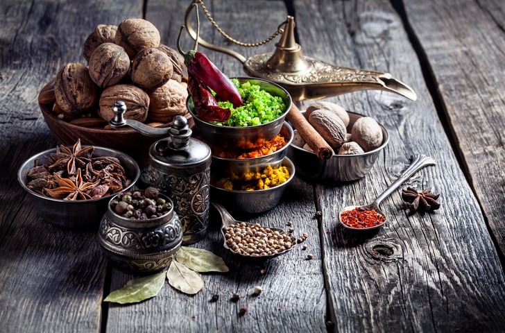 Spices, pepper grinder, spoon with seeds a grey wooden background