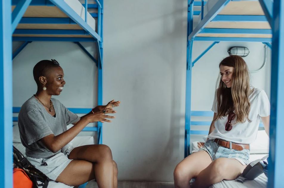 Women Sitting on Bunk Beds, Talking and Smiling