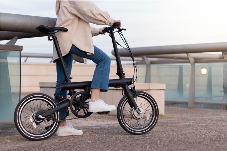 Zero emission concept. Cropped woman's legs riding an electric bicycle as transport around the city wearing a casual outfit