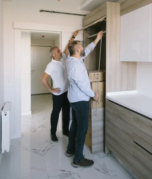 man measuring a cabinet with another man