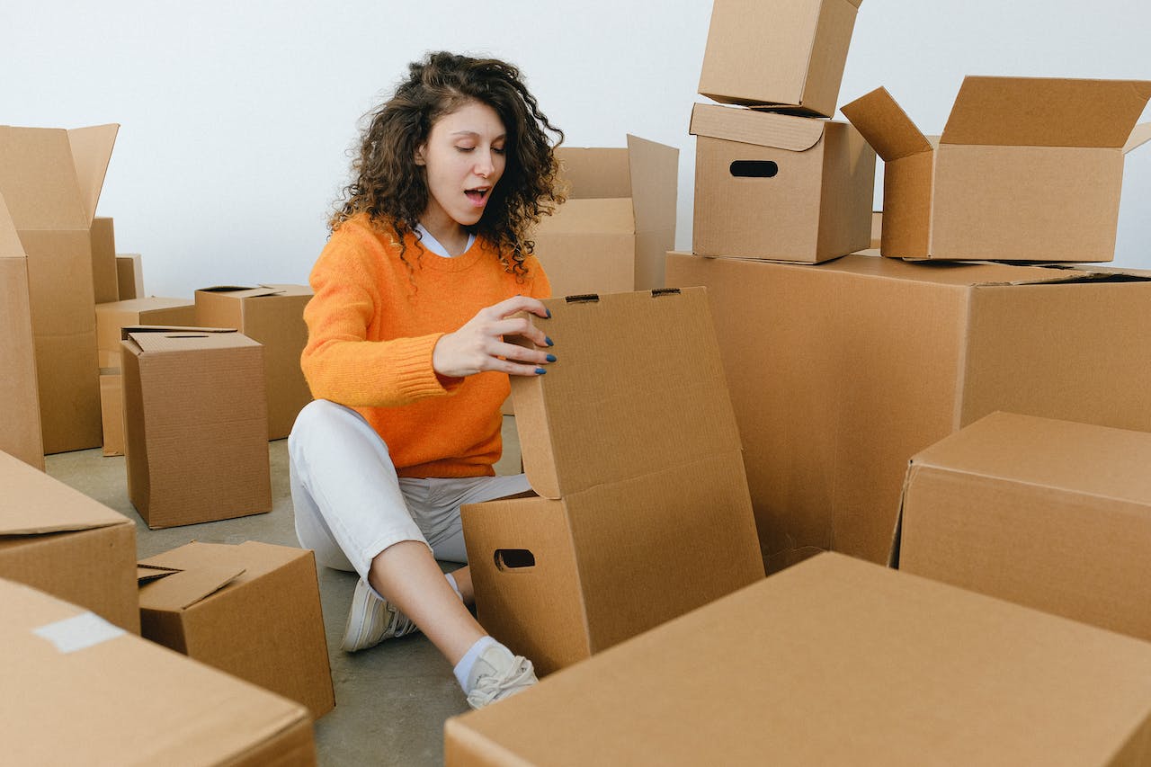 surprised young woman opening cardboard box after delivering parcel