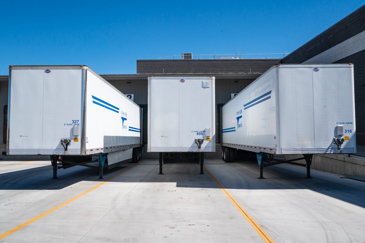 three white-enclosed trailers