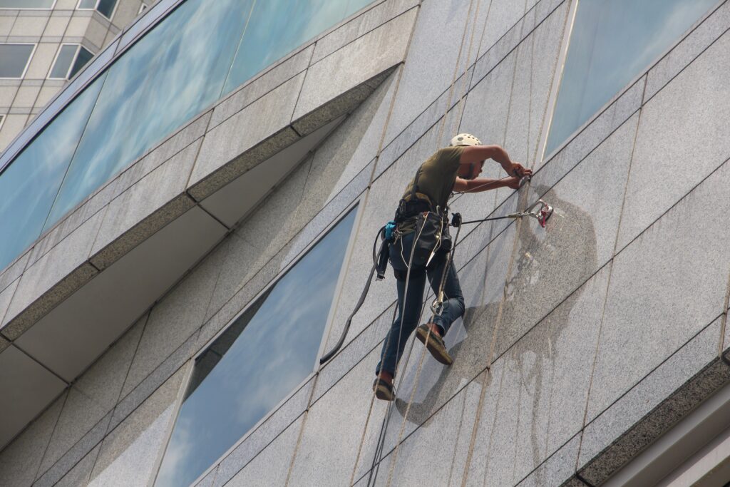 a man cleaning the outside window of a building image