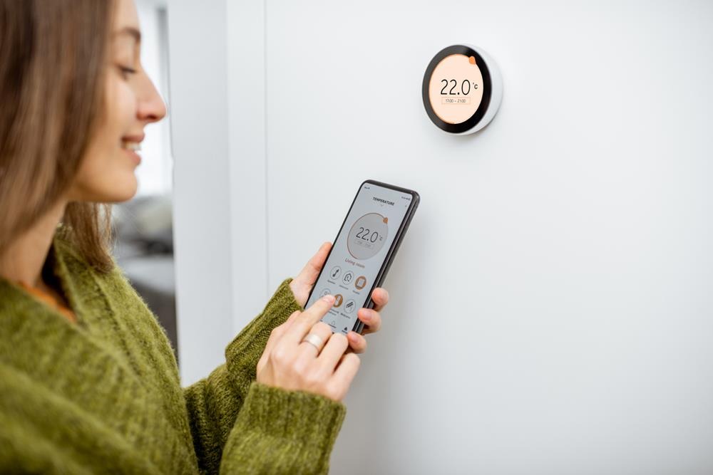 Woman regulating home temperature with a thermostat