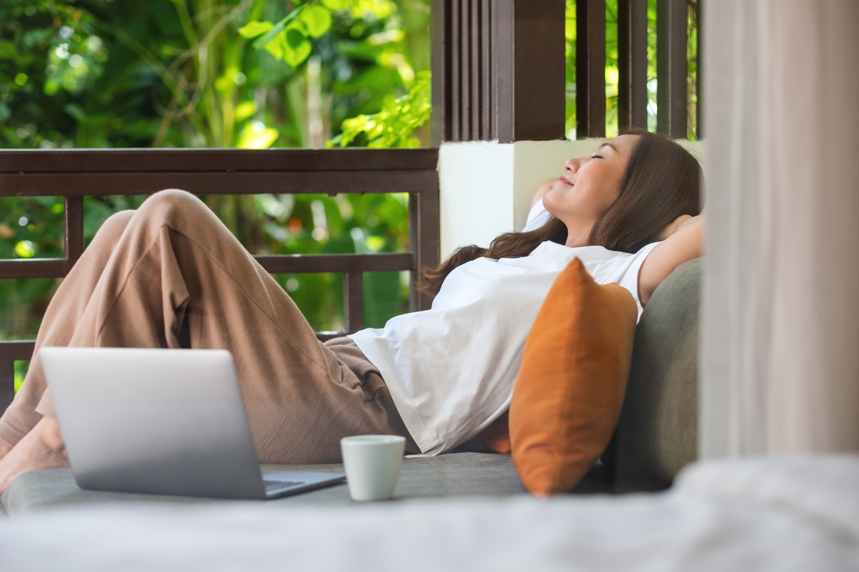 Woman resting on a sofa with a laptop open