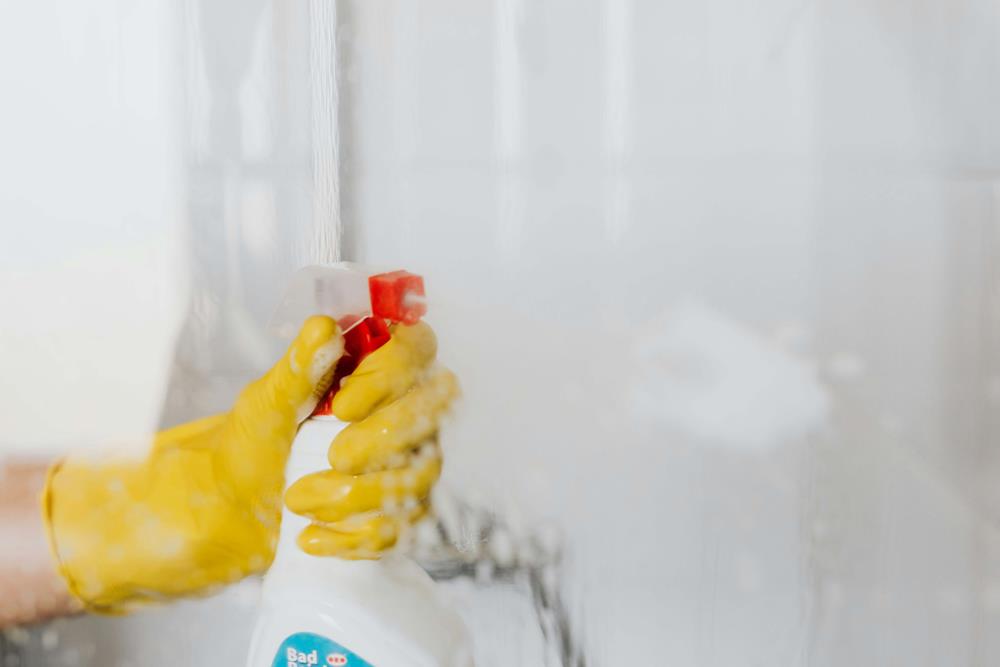 Spraying a cleaning solution on shower glass