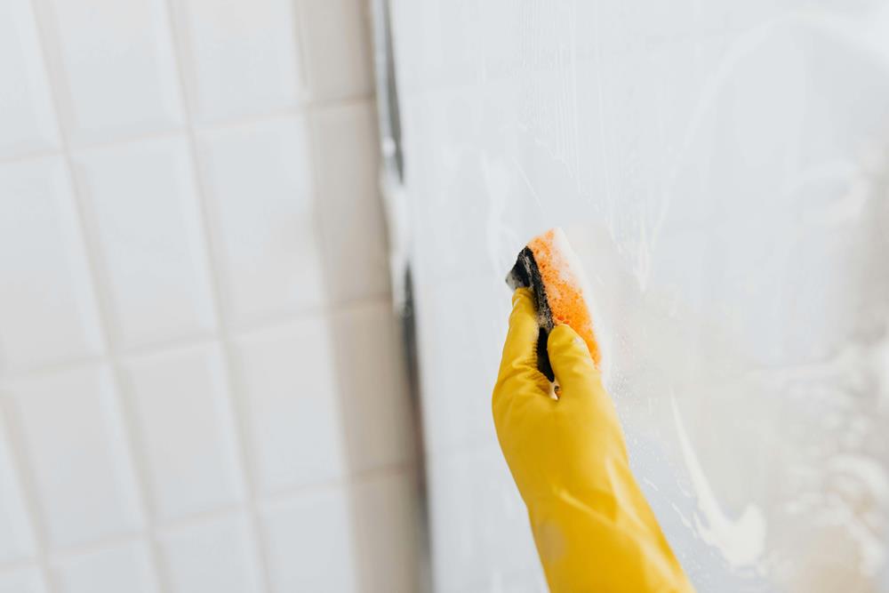 Using a sponge to wipe and clean shower glass