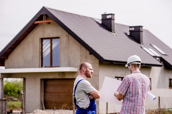 architect and builder talking outside a house being constructed