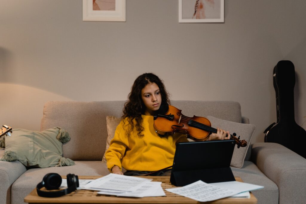 A girl watching a video while holding a violin image