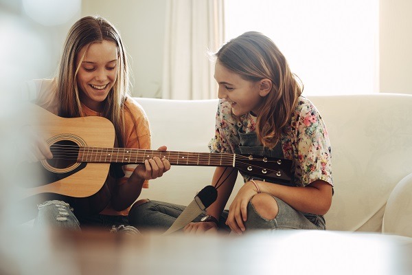 Happy girls playing guitar at home