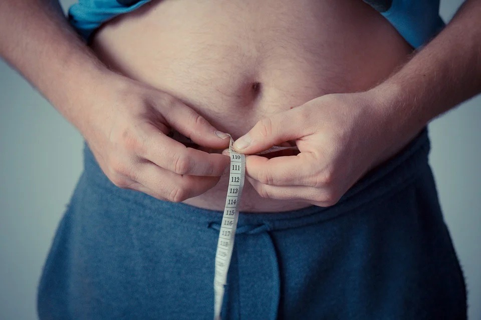 guy measuring his waistline with a tape measure