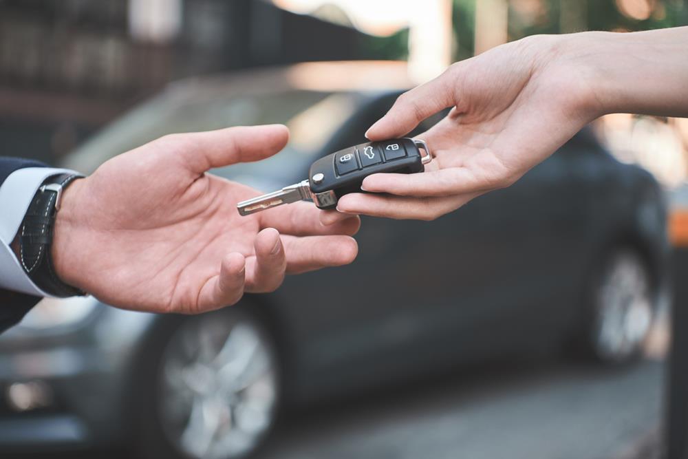 A man receiving car keys and a remote starter from a saleswoman