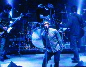 Oasis playing live. NME states, “as (What’s the Story) Morning Glory Emerged to colossal sales, it became clear that while Blur has won the battle, Oasis was winning the war
