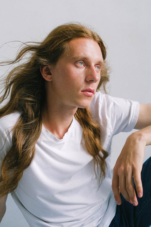 a man with long hair and wearing a white shirt