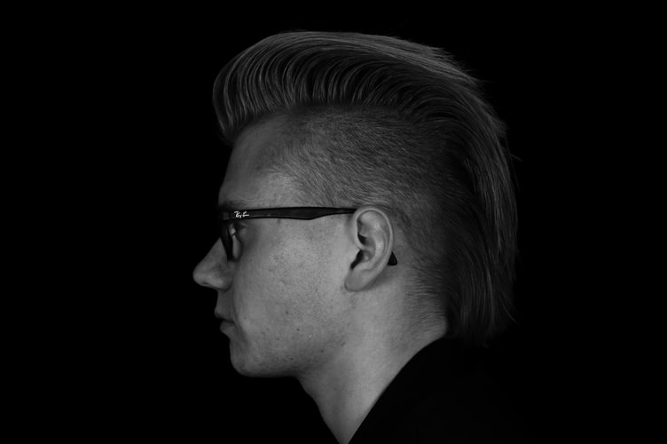 black and white picture of a man in a side profile, wearing glasses and an undercut
