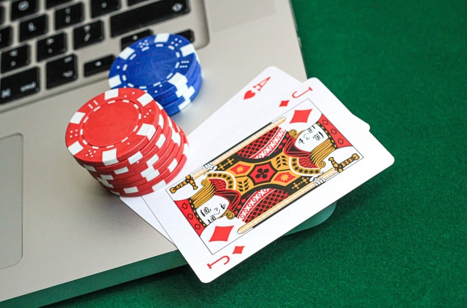 poker chips and card on top of a laptop keyboard