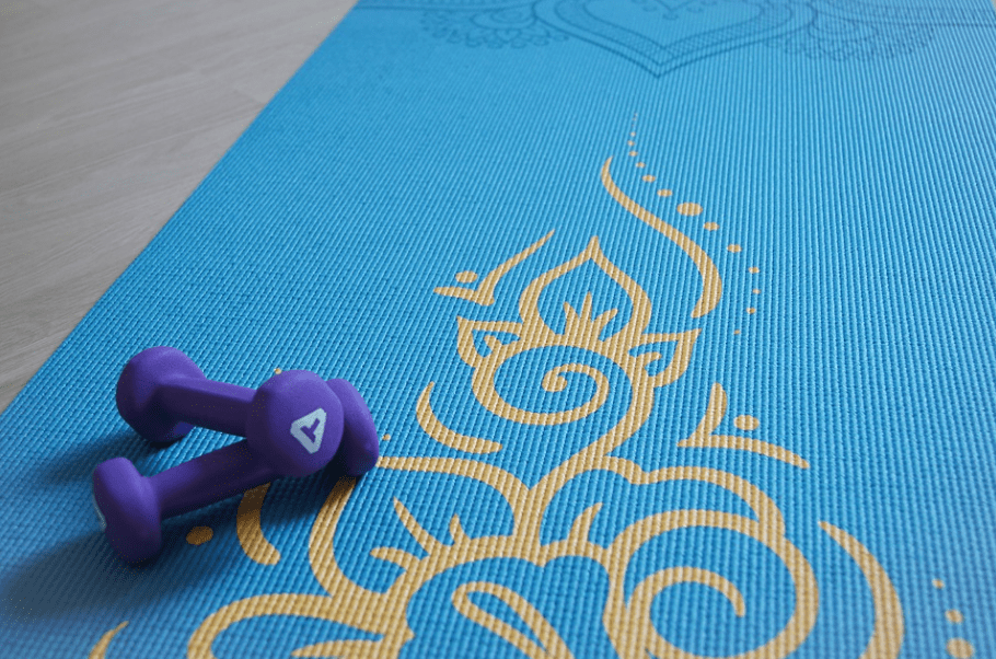 пара фиолетовых гантелей на синем коврике для йоги